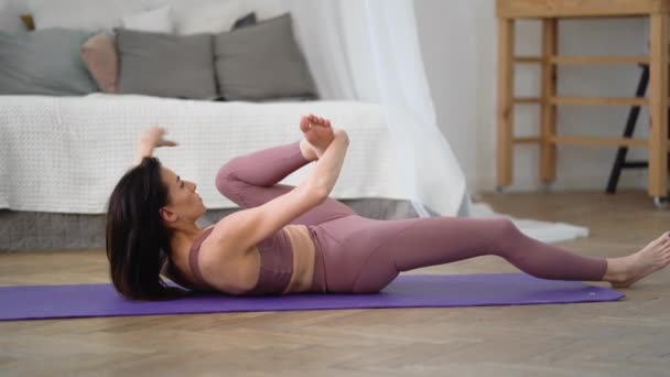 Kaukasisk kvinna i sportkläder utför yoga yoganidrasana, Yogic Sleep Pose — Stockvideo