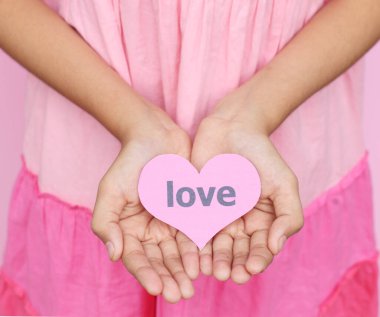 Aşk konsepti - Pembe elbiseli genç bir kız başka bir Sevgililer Günü 'ne kalp etiketiyle elini verir