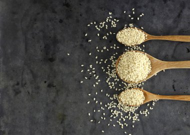 Tahta kaşıkta siyah zemine karşı kuru susam tohumunun üst görünümü