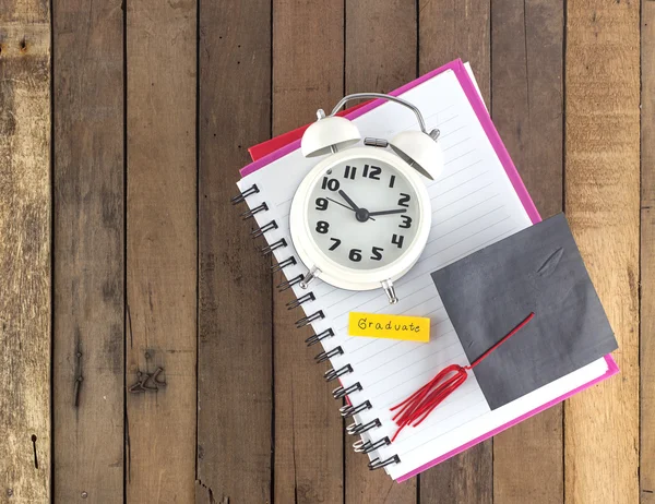 Graduiertenmütze und Uhr am Notizbuch — Stockfoto