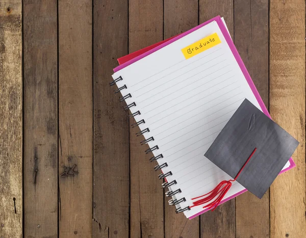 Capa de graduação no notebook contra fundo de madeira — Fotografia de Stock