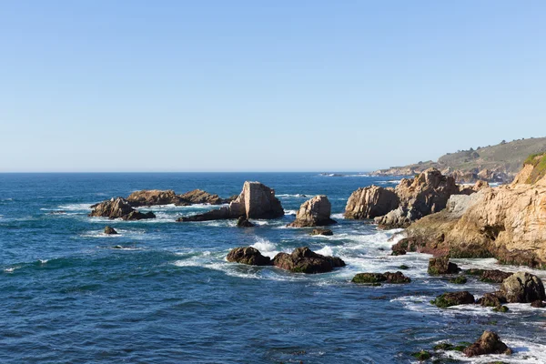 Rocky cliff on pacific ocean ocean shore in northern California next to Big Sur state park with waves and rocks — Stock Photo, Image