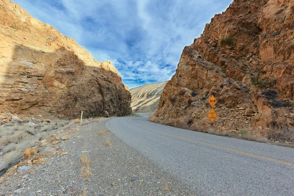 Kurve auf Death-Valley-Straße zwischen roten Felsen mit Verkehrszeichen — Stockfoto