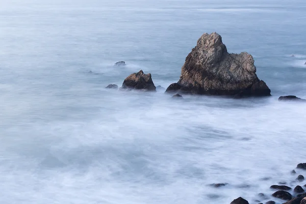 在晚上与模糊波海洋沿海岩 — 图库照片