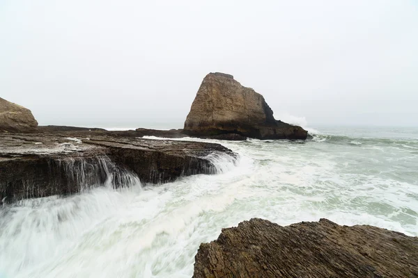 Океанічні хвилі, що розпадаються на прибережних скелях — стокове фото