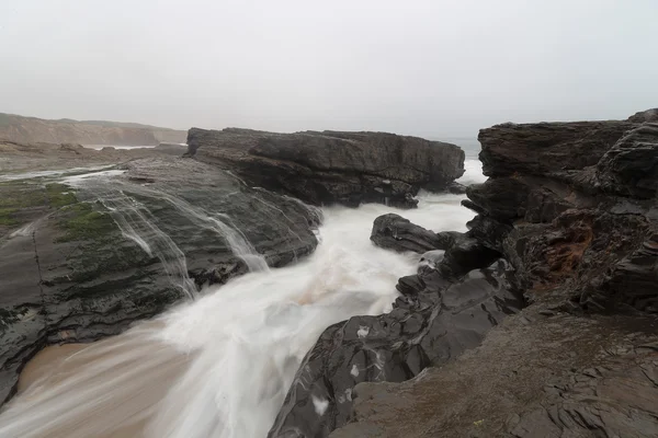 Verschwommene Meereswellen, die auf Felsen an Land fließen — Stockfoto