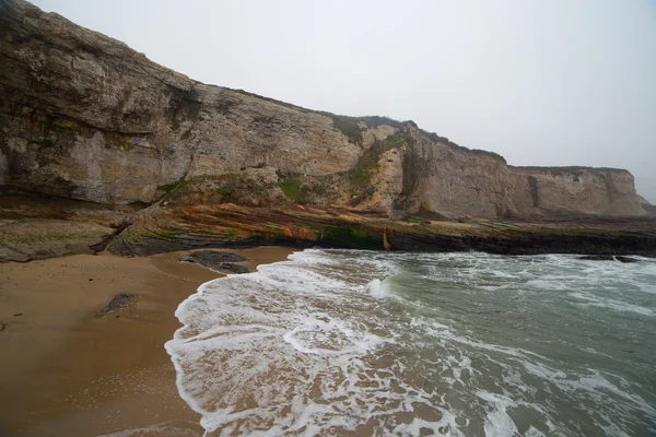 Cliff oceano com ondas brilhantes listradas rochas costeiras — Fotografia de Stock