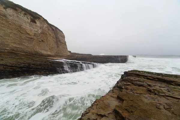 Океанічні хвилі, що розпадаються на прибережних скелях — стокове фото