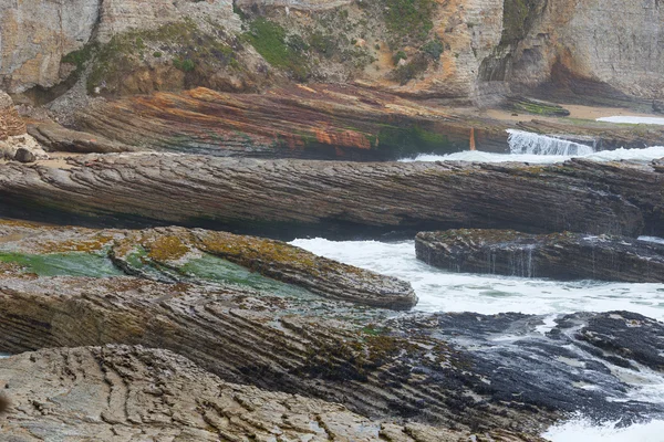 Cliff oceano com ondas e rochas costeiras listradas brilhantes — Fotografia de Stock