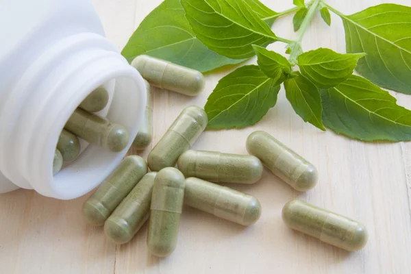 Herb capsules spilling out of a bottle — Stock Photo, Image