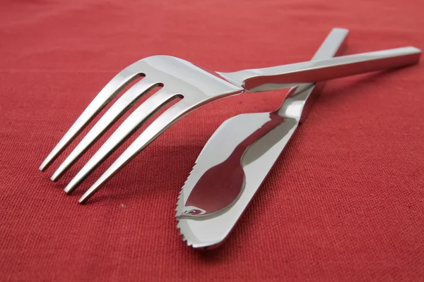 Tenedor y cuchillo sobre mantel rojo — Foto de Stock