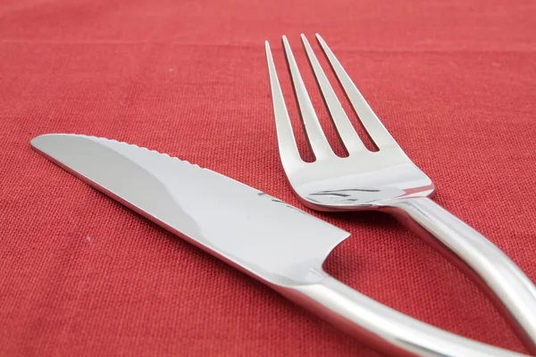 Tenedor y cuchillo sobre mantel rojo — Foto de Stock