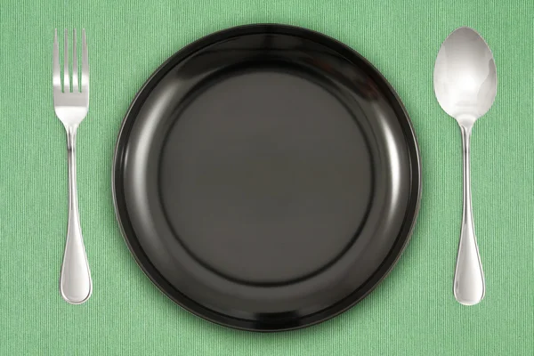 Schwarzer Teller auf grünem Hintergrund — Stockfoto