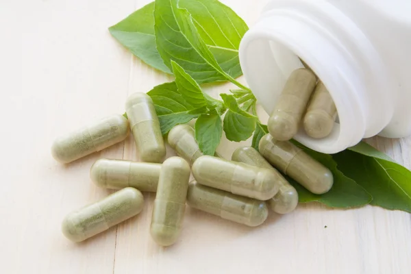 Herb capsules spilling out of a bottle — Stock Photo, Image