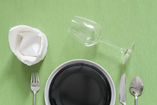 Abendessen auf einem schwarzen Teller mit silberner Gabel und Löffel — Stockfoto