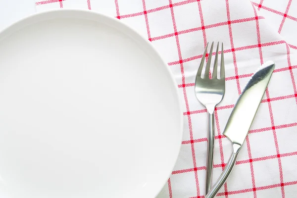 Cuchillo plato blanco y cuchara tenedor sobre mantel rojo a cuadros — Foto de Stock