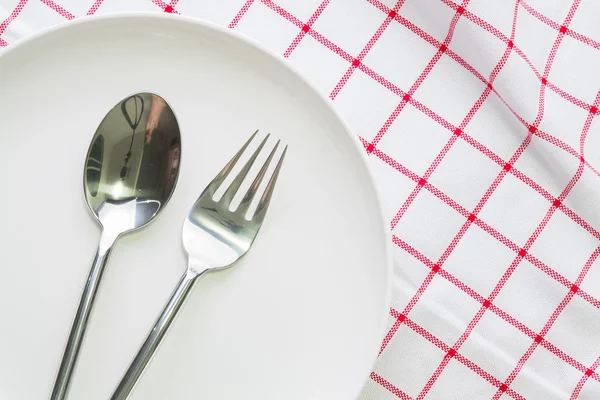 Placa branca e colher de garfo na toalha de mesa vermelha verificada — Fotografia de Stock