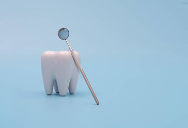 Mavi arkaplanda diş modeli ve dişçi aracı