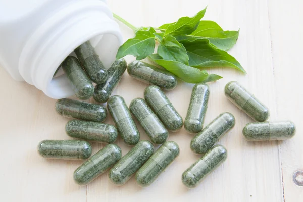 Herb capsules spilling out of a bottle — Stock Photo, Image