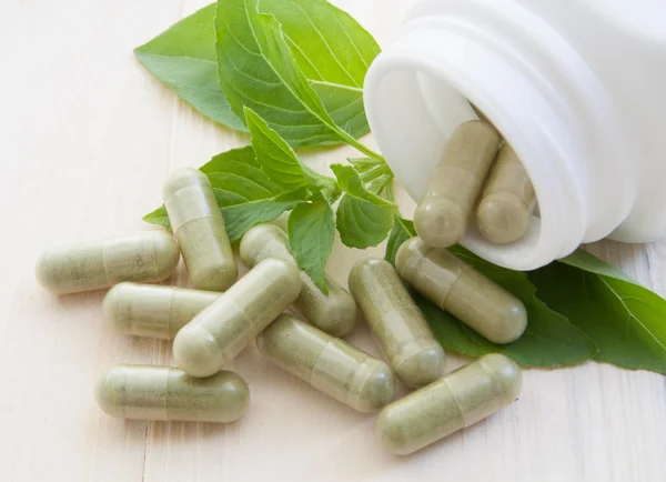 Herb capsules spilling out of a bottle — Stock Photo, Image