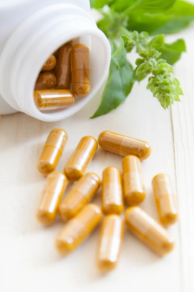 Herb capsules spilling out of a bottle — Stock Photo, Image