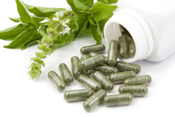 herb capsules spilling out of a bottle  