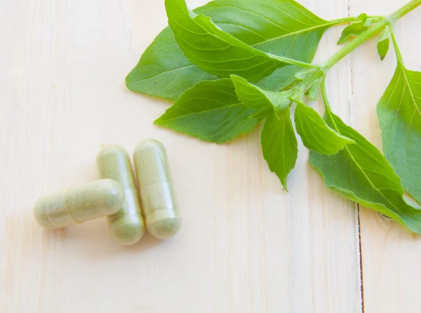 Herb capsules spilling out of a bottle — Stock Photo, Image