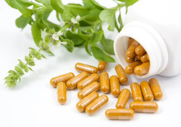 Herb capsules spilling out of a bottle — Stock Photo, Image