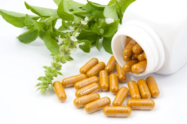 Herb capsules spilling out of a bottle — Stock Photo, Image