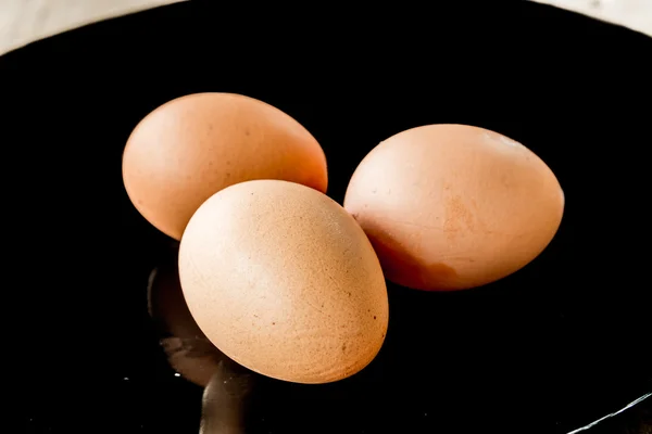 Wyświetlić zbliżenie trzy brązowe jaja na blackdisk — Zdjęcie stockowe
