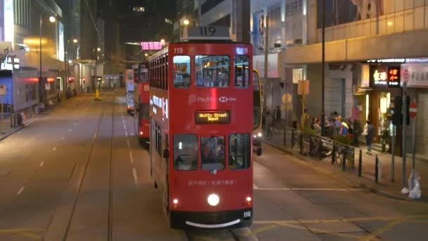 Красные двухэтажные автобусы на улице, движущиеся к камере ночью — стоковое видео
