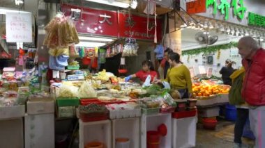 HONG KONG - 23 HAZİRAN 2020 Gıda pazarının önünden geçen yaşlı adam ve arka planda yiyecek satın alan insanlar