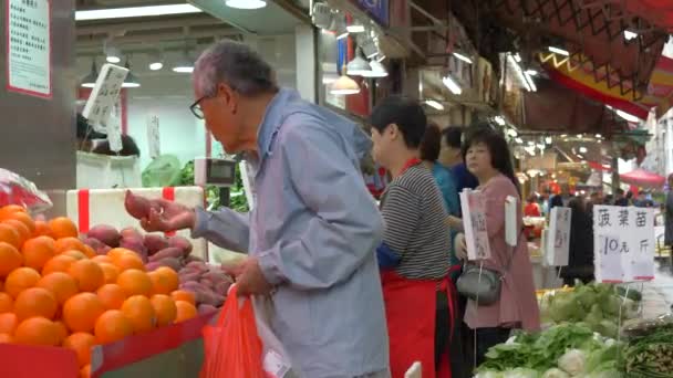 Un anciano recogiendo mandarinas en el mercado de alimentos por la noche — Vídeo de stock