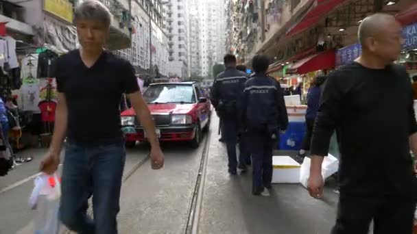 Hong Kong - 23 de enero de 2020: los chinos caminan por una calle llena de gente y pasa un coche — Vídeo de stock