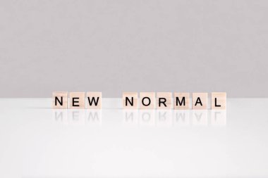 Tahta harf küplerinin yan görünüşünden oluşan yeni normal ifade. Covid-19 salgınından sonra sosyal mesafeli yaşam. Dükkan, alışveriş merkezi, kafe, otelin yeniden açılması. Karantina bitti, tecrit. Güvenli yaşam tarzı
