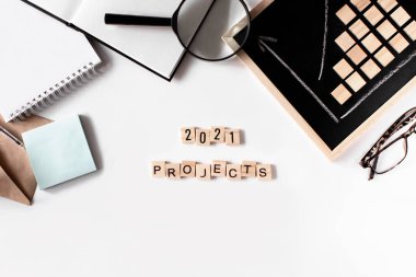 2021 proje cümlesi ahşap harflerden oluşuyor. İş düzlüğü beyaz arka planda yatıyordu. Planlar, 2021 hedefleri, iş istatistikleri. Kariyer, para, başarı konsepti. İşyeri organizasyonu.