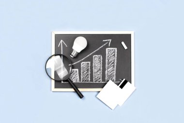 İş dairesi mavi arka planda yatıyordu. Tebeşir tahtası, büyüteç, ampul, kredi kartı, karatahta. İş istatistikleri. Kariyer, para, başarı konsepti. İşyeri organizasyonu.