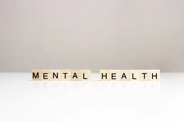 Frase de salud mental hecha de letras de madera en la vista lateral de la mesa blanca. Sensibilizar sobre los problemas de salud mental. Concepto de apoyo psicosocial. Salud emocional, bienestar, problemas comunes — Foto de Stock