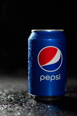 Siyah arkaplanlı editör fotoğrafının üzerine su damlatan Pepsi soda kutusu. Pepsico marka şirketi. Karbonatlı tatlı içecek. Pepsi logosu