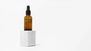 Damlatan cam pipet şişesi, okaliptüs ile beton kaidesel hareket animasyonu, beyaz arka plan, kopyalama alanı. Serum, podyumda asit. Doğal kozmetik. Spa, güzellik, cilt bakımı