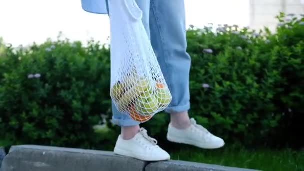 Woman Jeans Walking Holding White Mesh Bag Fruits Eco Friendly — Stock Video