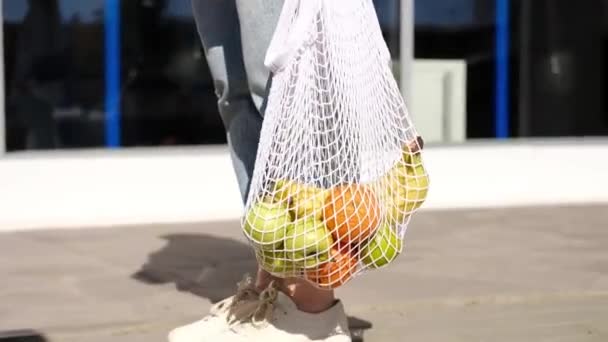 Жінка Джинсах Стоїть Тримає Білий Мішок Сітки Фруктами Екологічно Чиста — стокове відео