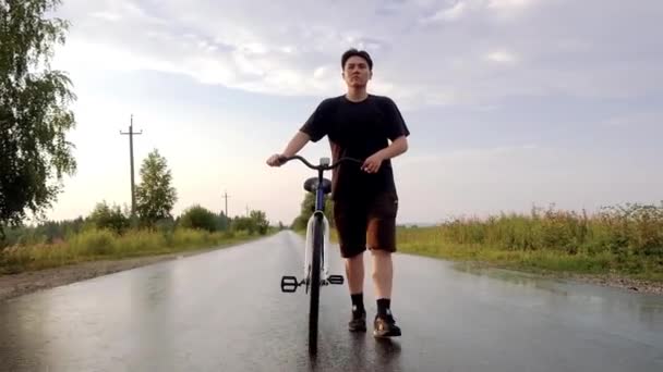 Young man alone walking on road with bicycle at countryside. Summer activity, healthy lifestyle, workout, sport, fitness. Alone person in nature. Riding bicycle. Having fun outdoors. — Stock videók