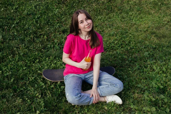 Smiling Young Woman Pink Shirt Sitting Skateboard Green Grass Holding — Stock Photo, Image