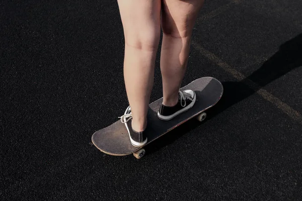 Женщины в черных шортах и кроссовках стоят, катаясь на скейтборде снаружи. Летняя активность, здоровый образ жизни, тренировки, спорт, фитнес, верховая езда. Один-одинёшенек. Веселитесь на открытом воздухе. — стоковое фото