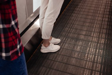 Yürüyen merdivende duran kot pantolonlu kadın. Çevre dostu, yeniden kullanılabilir alışveriş çantası. Portakallar, elmalar, pamuk iplik torbasında muzlar. Sıfır atık ve plastiksiz kavram.