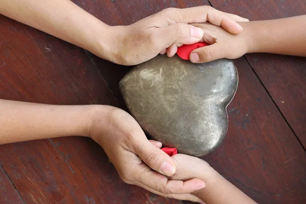 Manos de mujer y niño sosteniendo corazón rojo y metal en forma de . —  Fotos de Stock