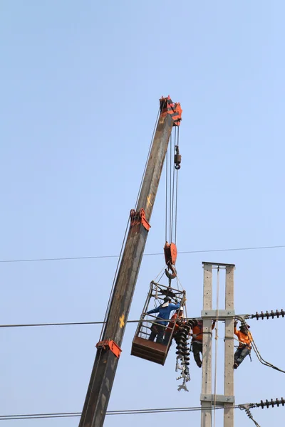Electricista trabajando en altura conectando un cable de alto voltaje — Foto de Stock