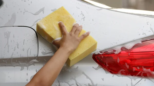 Mulher Lavar um carro com uma esponja e sabão . — Fotografia de Stock