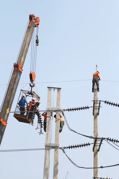 Eletricista trabalhando em altura conectando um fio de alta tensão . — Fotografia de Stock
